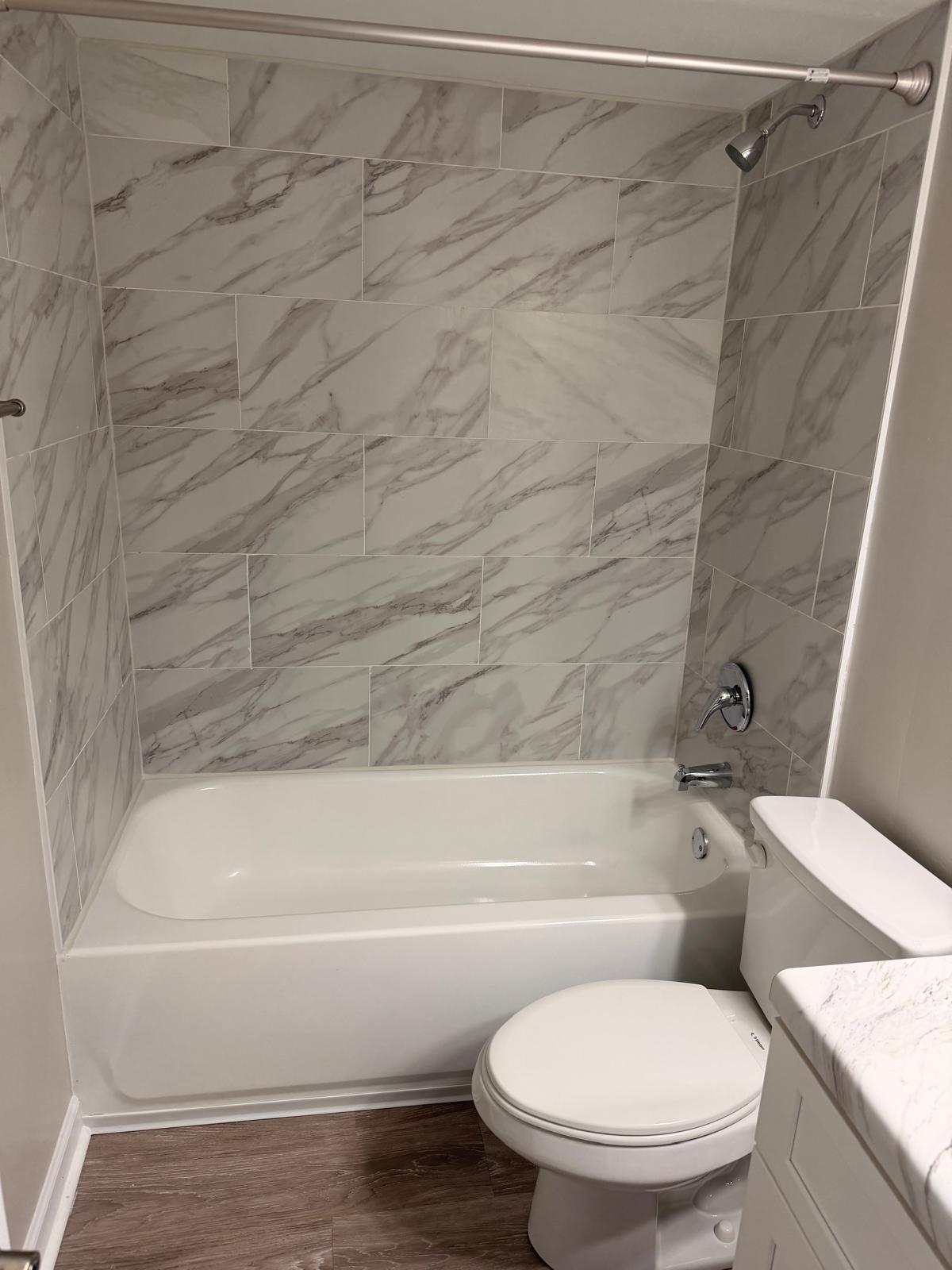 Completed apartment bathroom with finished tub, tile surround and new flooring after a make-ready turn