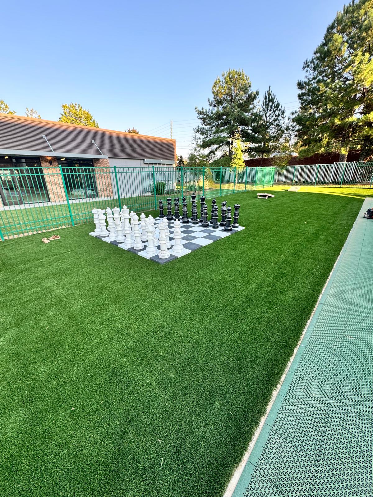 Artificial turf recreation area with a giant outdoor black and white chess set
