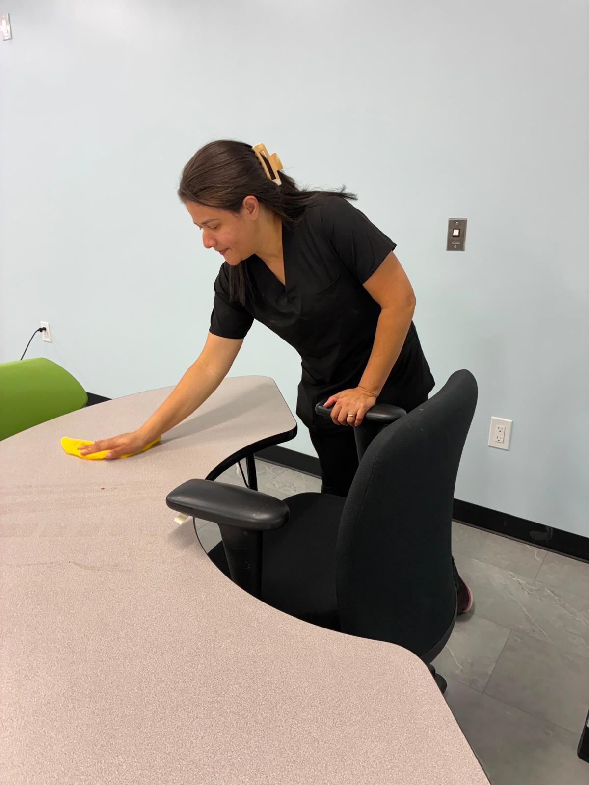 Team member performing detailed surface cleaning in a commercial workspace