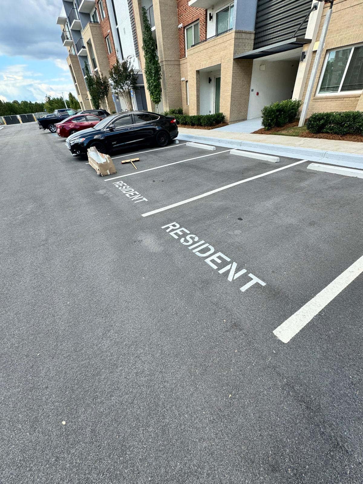 Completed white parking stalls with RESIDENT pavement stencils