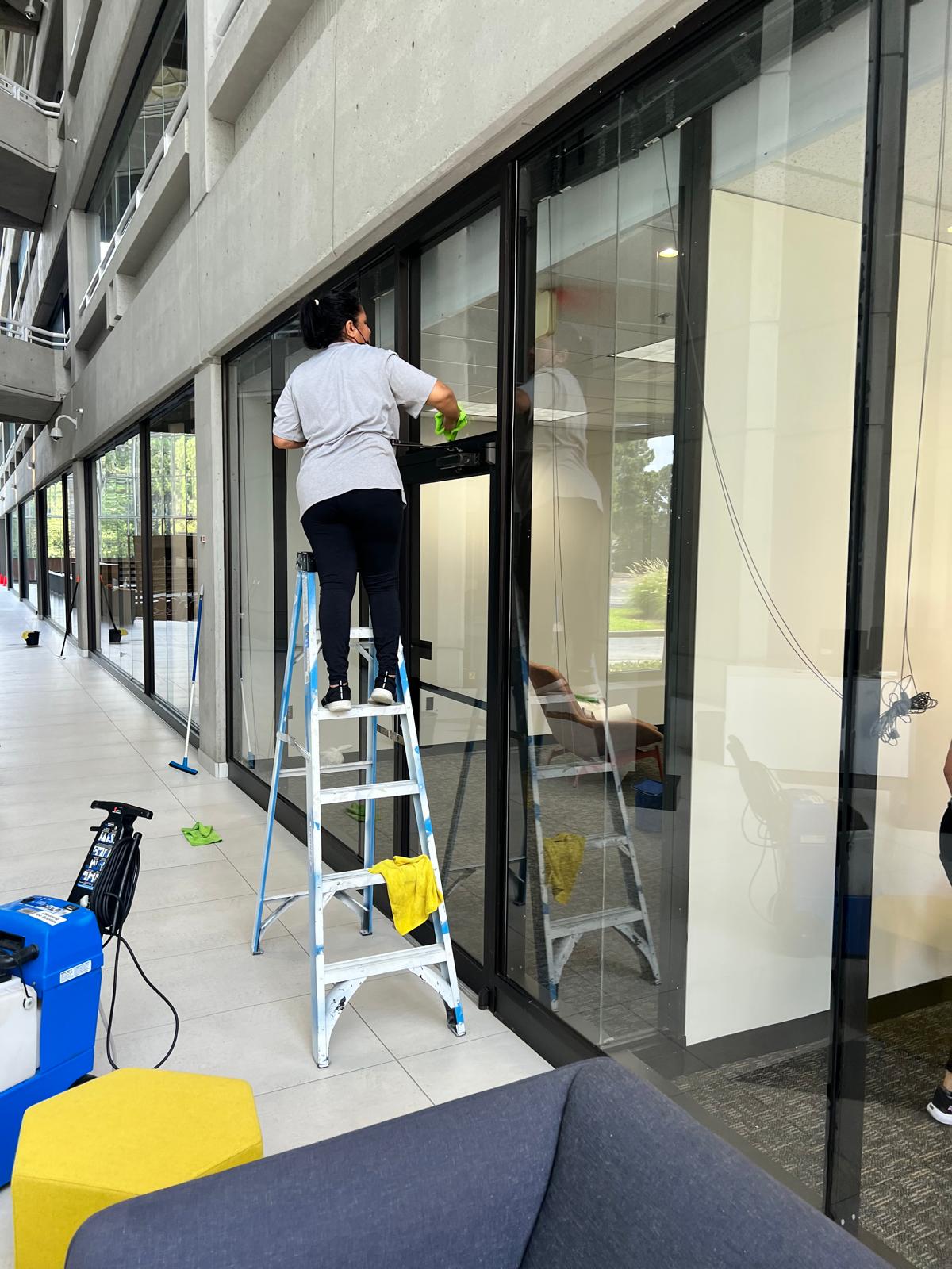 DJ7 Solutions crew member detail cleaning interior glass on a commercial property