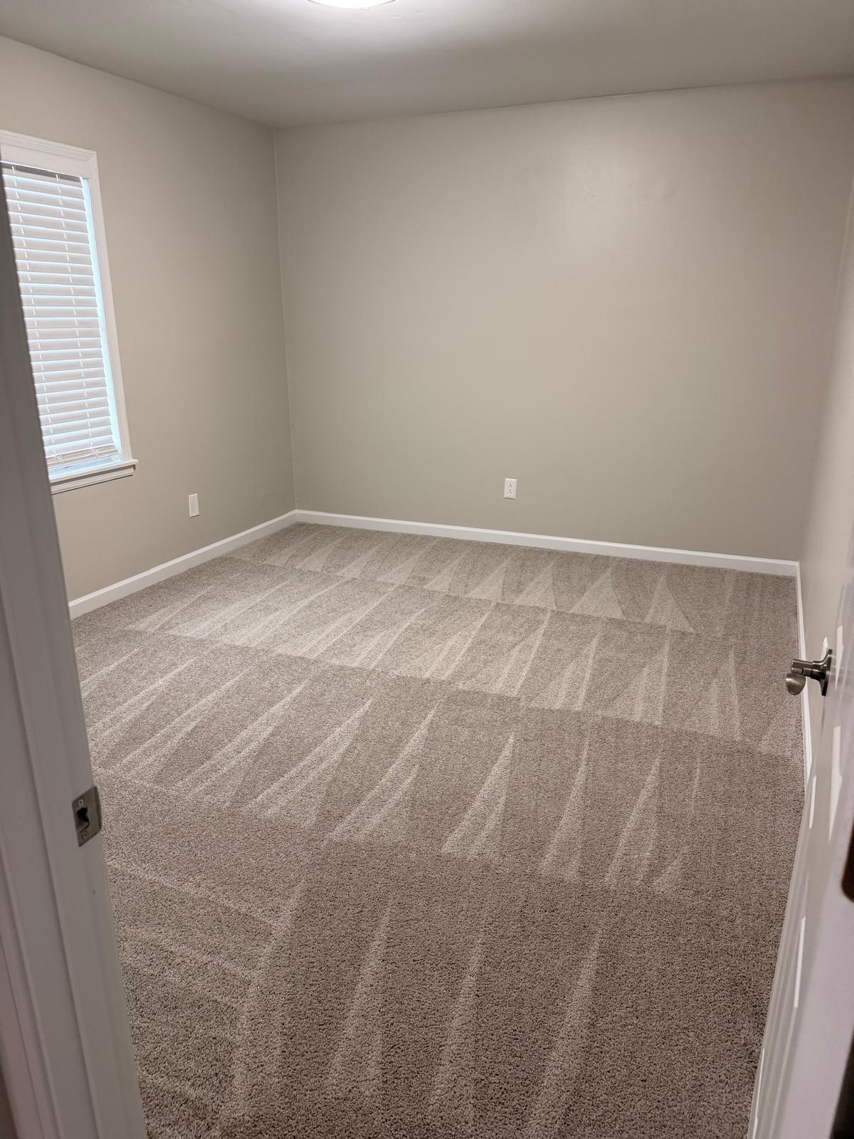 Completed apartment bedroom with freshly cleaned carpet, painted walls and baseboards, ready for move-in